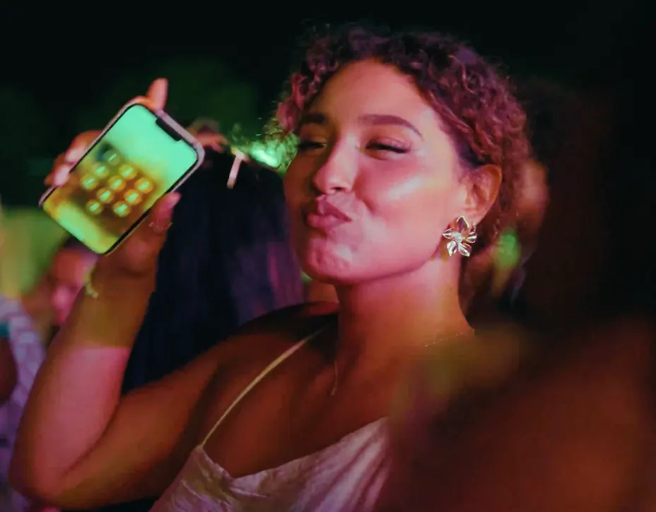 Jeune femme en soirée, smartphone à la main, sous une lumière colorée