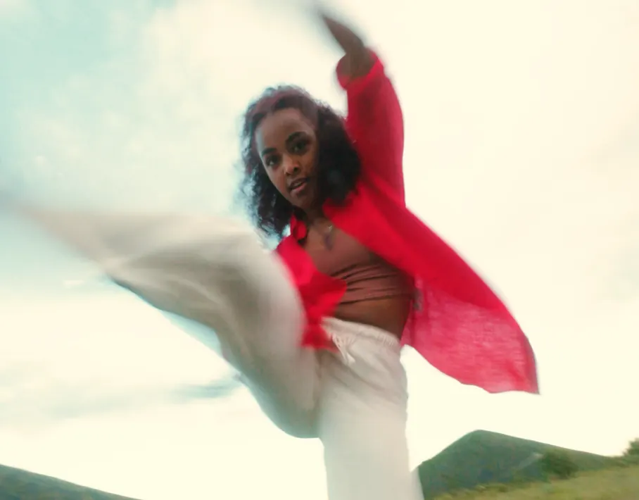 Danseuse en chemise rouge en plein mouvement, le tissu au vent
