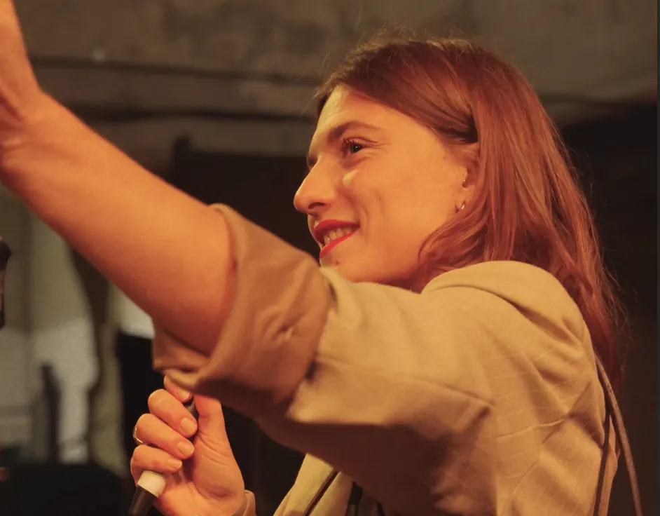 Femme en veste beige tendant le bras dans un intérieur chaleureux