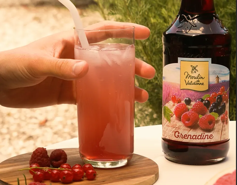 Verre de grenadine à côté d’une bouteille Moulin de Valdonne