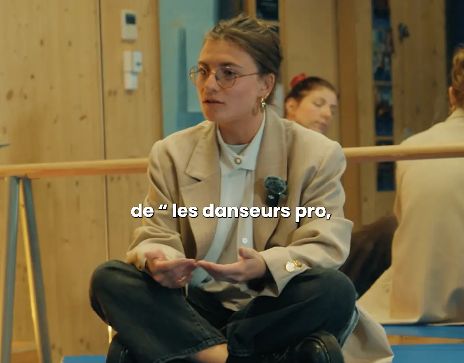 Femme en blazer assise en tailleur, interviewée dans un studio de danse