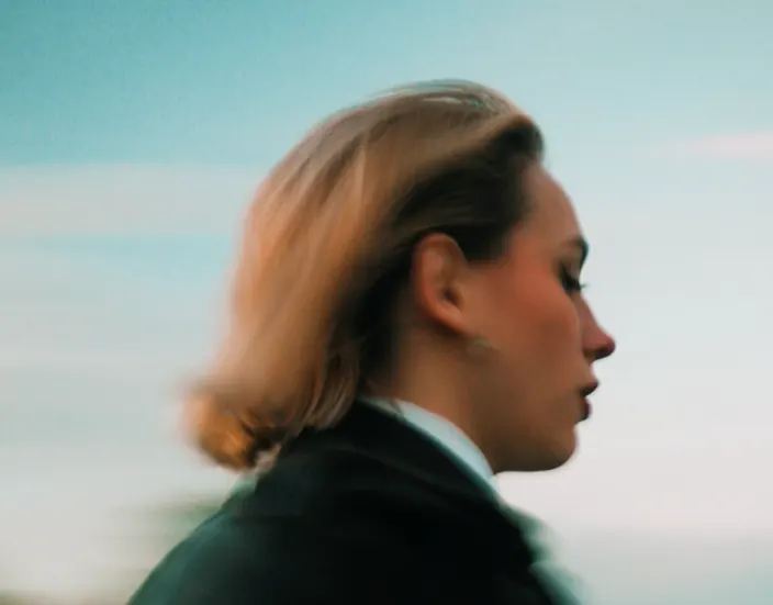 Profil d’une femme en mouvement devant un ciel pâle