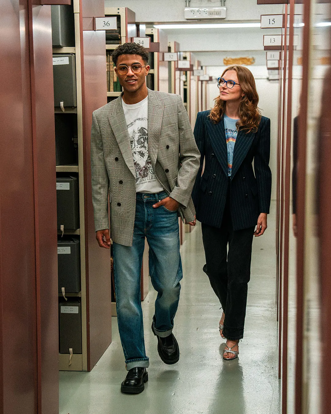 Un duo marche dans une allée d’archives, look décontracté chic