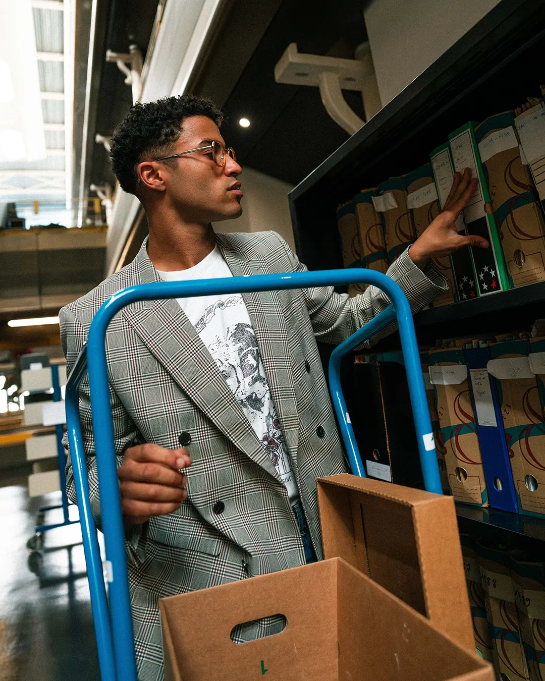 Jeune homme poussant un chariot de cartons d’archives