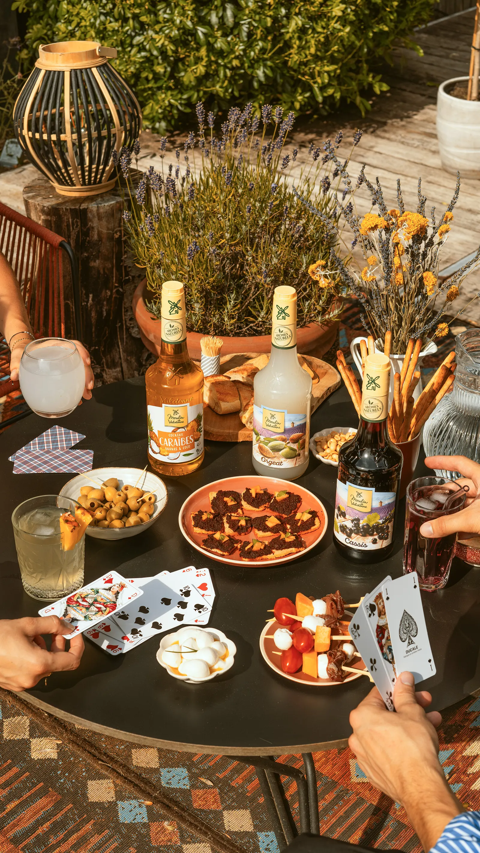 Partie de cartes à l’apéritif, sirops Moulin de Valdonne sur la table
