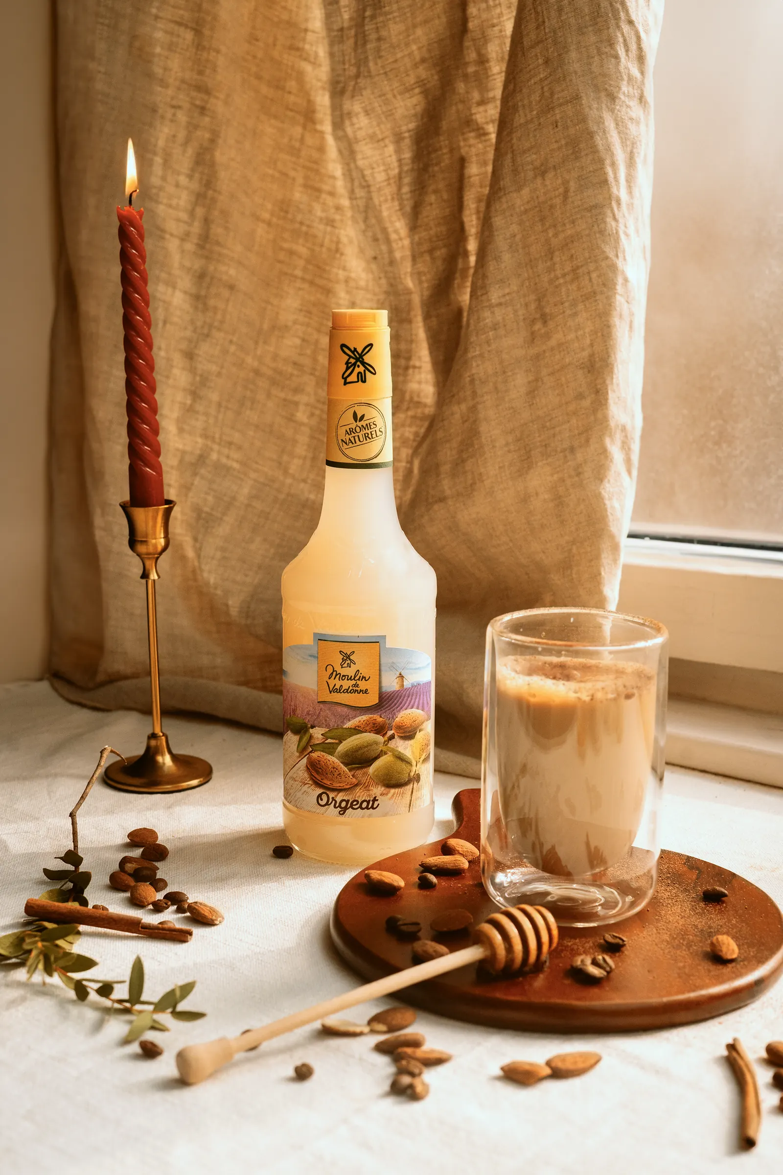 Sirop d’orgeat et boisson lactée à côté d’une bougie, ambiance d’automne